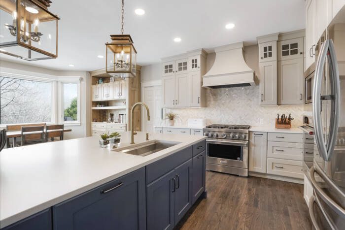 BKC Kitchen and Bath transitional kitchen with cream painted cabinets, blue painted center island, and natural hickory hutch