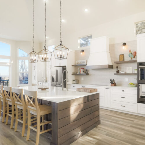 Cream and walnut kitchen design featuring white cabinetry, a large island with a wooden base, pendant lighting, and modern appliances, showcasing a bright and airy atmosphere in a contemporary home.
