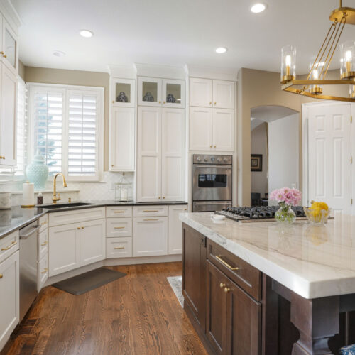 Elegant kitchen featuring white shaker cabinets, dark wood island, marble countertops, modern appliances, and decorative lighting, highlighting a sophisticated design suitable for inspiration in kitchen remodeling.