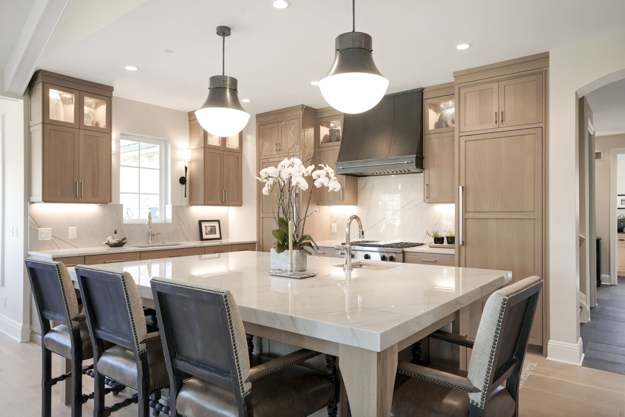 BKC Kitchen and Bath transitional kitchen with light wood cabinets, large center island and metal pendant lights