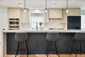 Modern kitchen island with bar stools, sleek cabinetry, integrated appliances, and stylish countertop, designed for entertaining and maximizing space in a contemporary home.